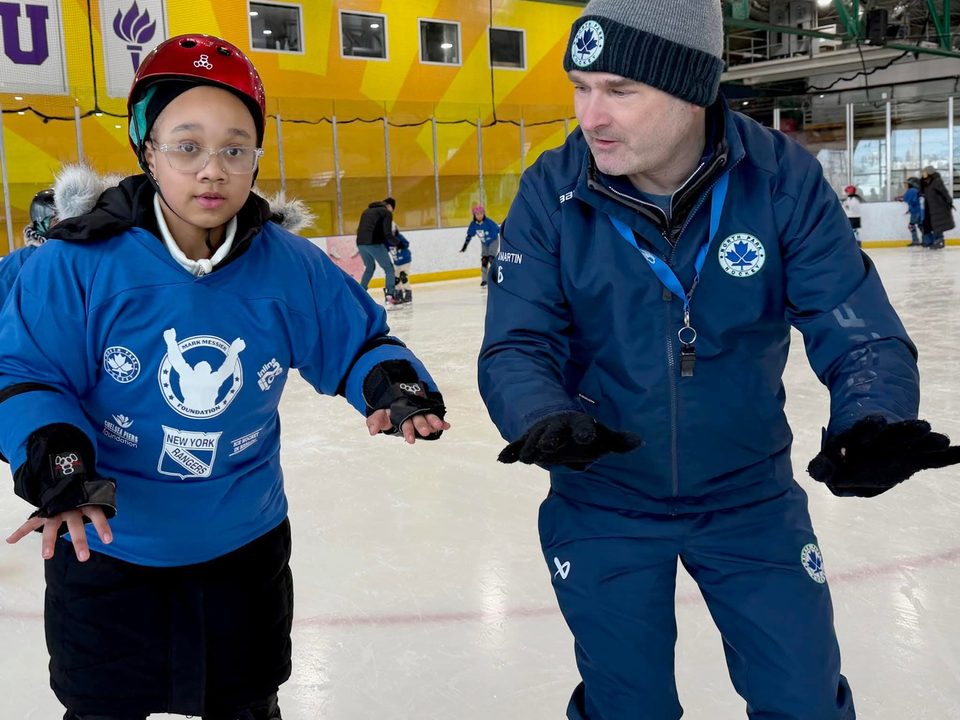 A North Park coach skating backward with a young player